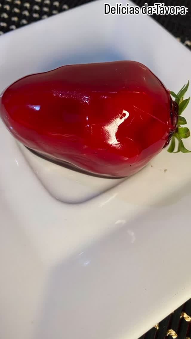 Morango do Amor com cobertura vermelha brilhante em prato branco.