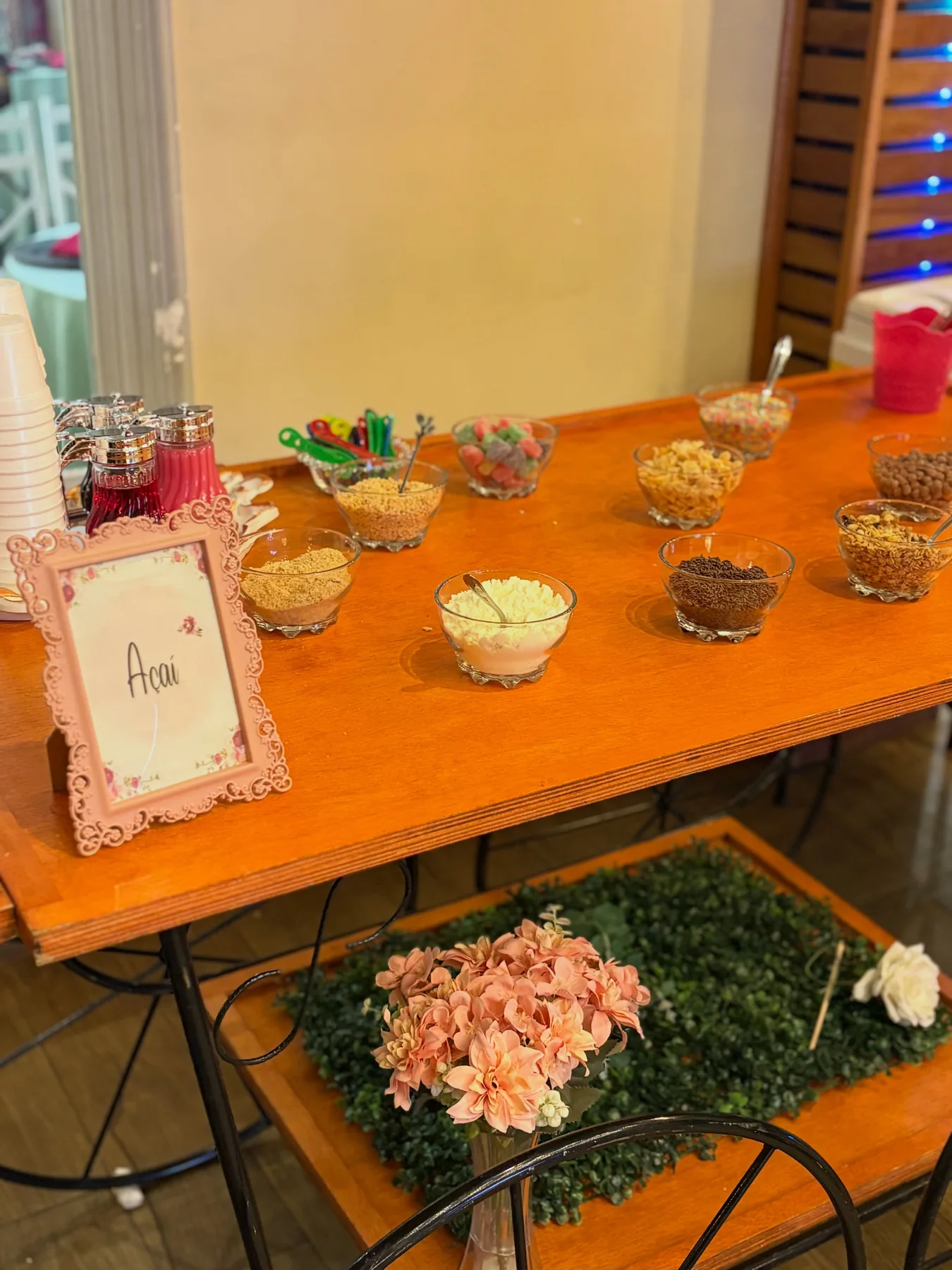 Mesa de estação de açaí com coberturas organizada para evento.